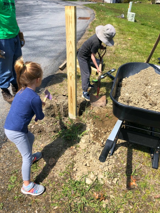 Kids helping put dirt back into a hole around a 4x4 mailbox pole