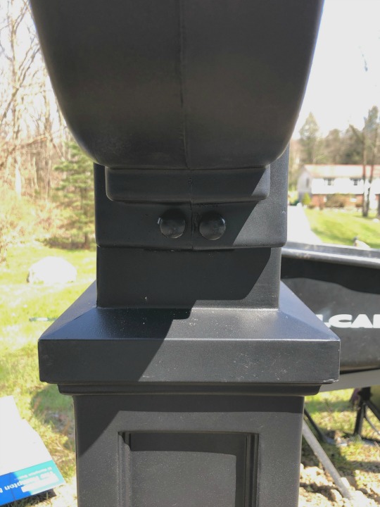 Black mailbox with screw covers covering the screws on the pole 