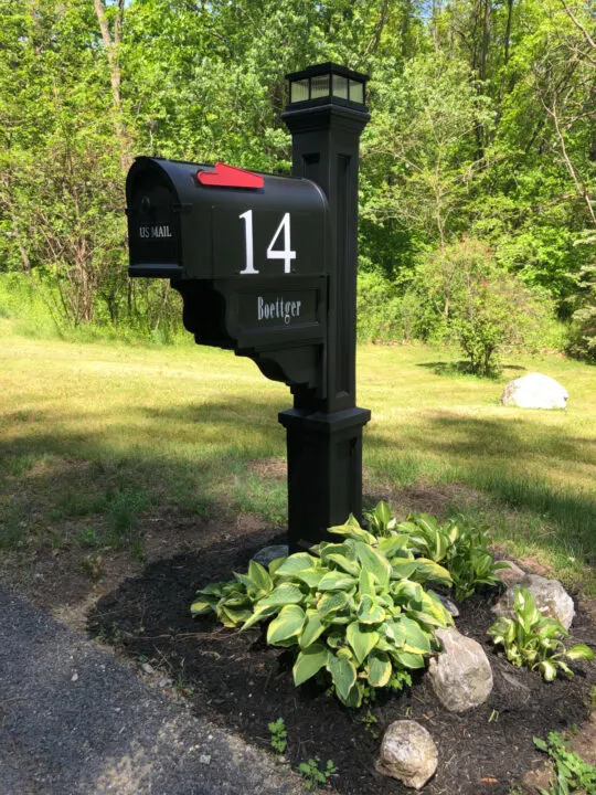 Black mailbox with large rocks and hostess planted around 