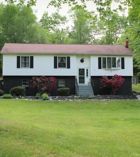 raised ranch home with black brick and red roof.