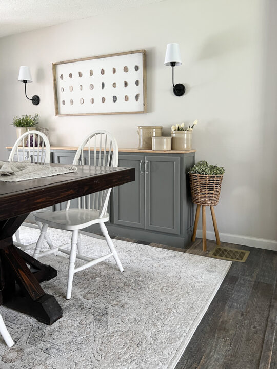 dining room with buffet, neutral rug and plant stand.