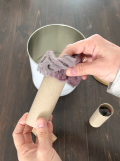 stuffing dryer lint into an empty toilet paper roll